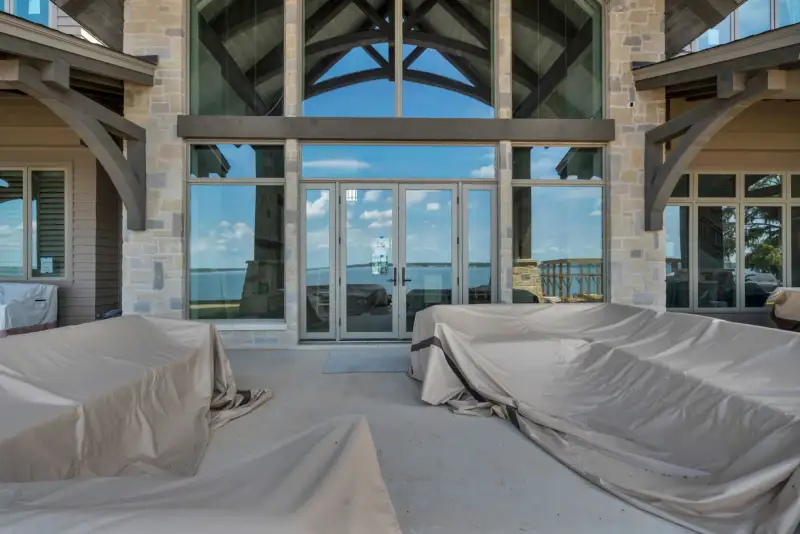 Double glass doors on a covered patio, flanked by stone columns and tall glass panels.