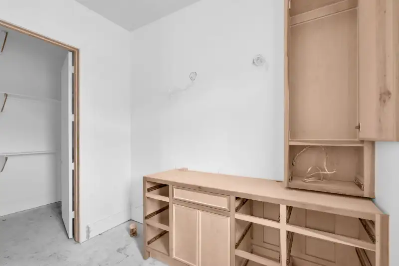 Room with a light wood base cabinet and tall cabinet beside a doorway to a walk-in closet.
