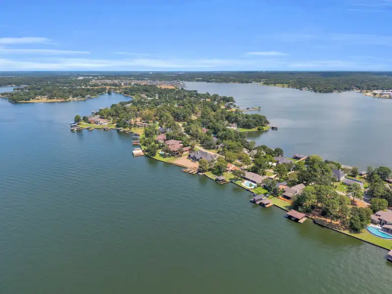 Aerial view of a shoreline with homes, boat docks, and open lake water on both sides.