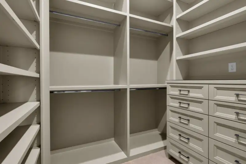 Walk-in closet with open shelving, hanging rods, and drawer units on the right.