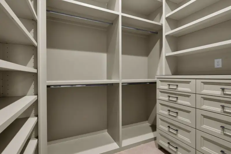 Walk-in closet with open shelving, hanging rods, and drawer units on the right.