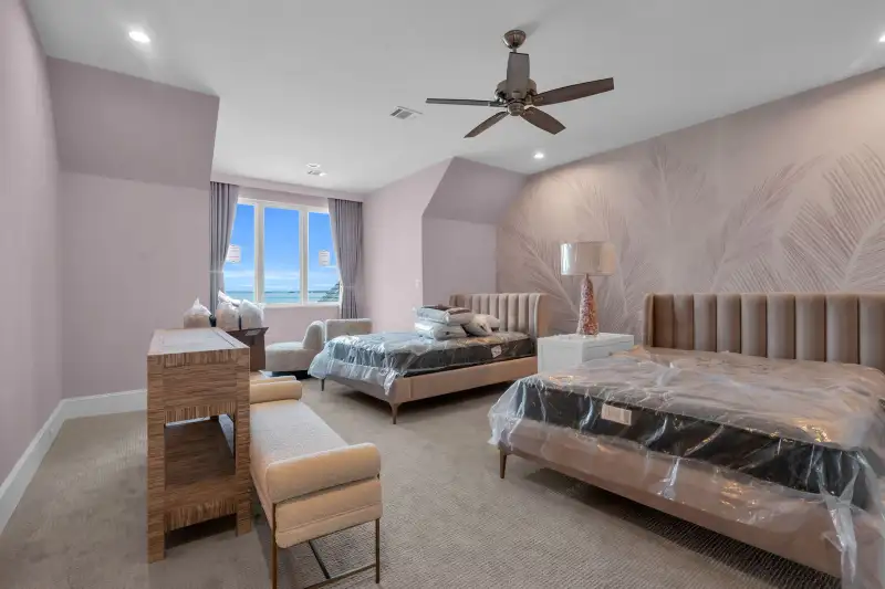 Bedroom with a leaf-pattern feature wall, a ceiling fan, and a bed with plastic on the mattress.