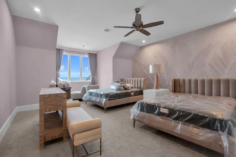 Bedroom with a leaf-pattern feature wall, a ceiling fan, and a bed with plastic on the mattress.