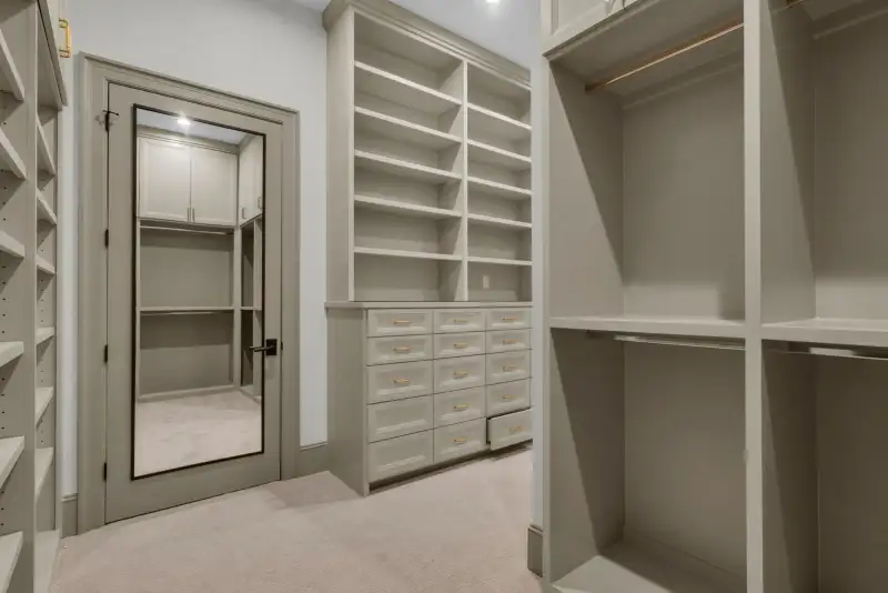 Closet with a mirrored door, drawer units, and open shelving on the far walls.