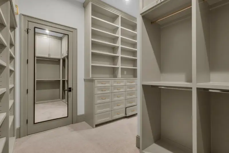 Closet with a mirrored door, drawer units, and open shelving on the far walls.