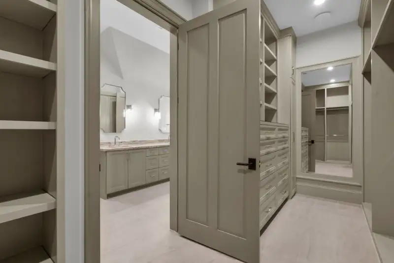 Walk-in closet with drawer units, open cabinetry, and a mirror on the far door.
