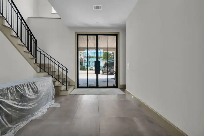 Entry foyer with a glass front door, a stair railing, and gray floor tile.