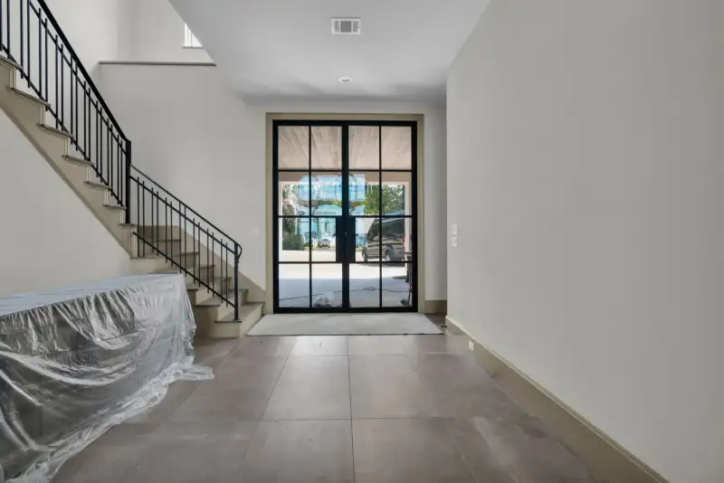 Entry foyer with a glass front door, a stair railing, and gray floor tile.