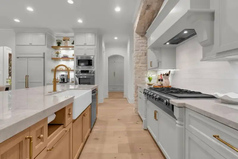 Kitchen view with a farmhouse sink in the island, a cooktop, and a white range hood.