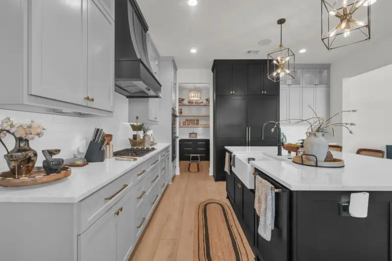 Kitchen with white cabinets, a black range hood, a farmhouse sink, and a patterned runner rug.