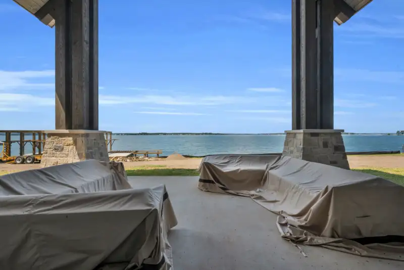 Covered patio with lake views, concrete floor, and furniture under protective covers.