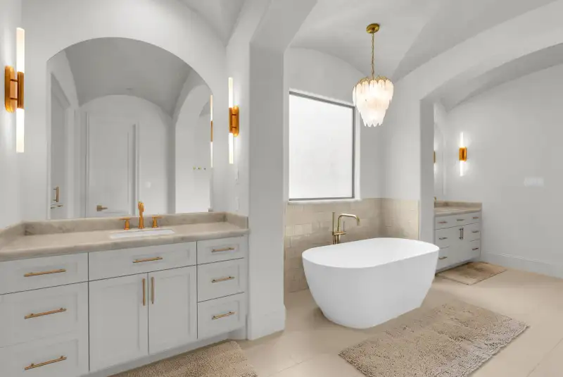 Primary bath with a marble-look vanity top, an arched mirror, and a freestanding tub by the window.