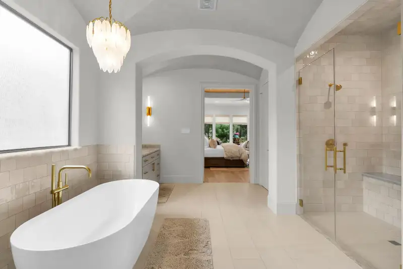 Primary bath with a freestanding tub, a view through an arched doorway to the bedroom, and a glass shower.
