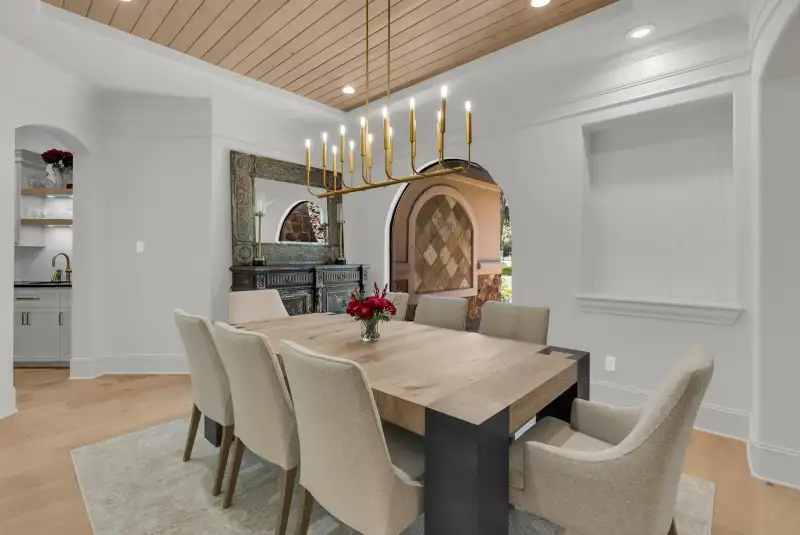 Dining room with a wood plank ceiling, a dining table with upholstered chairs, and a view into the kitchen.