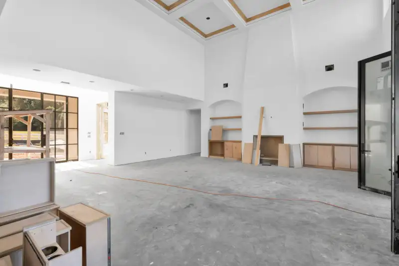 Two-story room with a coffered ceiling, built-in shelves, and a tall black-framed glass door at right.