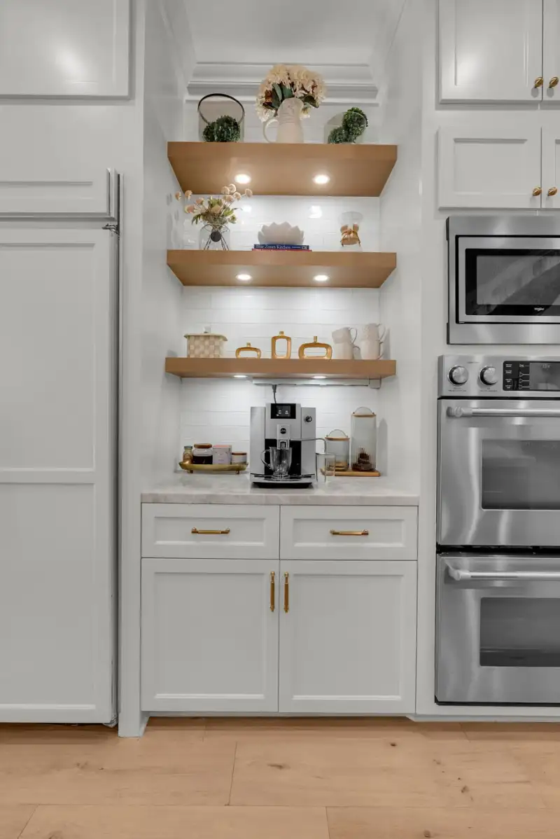 Coffee station with open wood shelves, an automatic coffee machine, and a microwave and double oven.