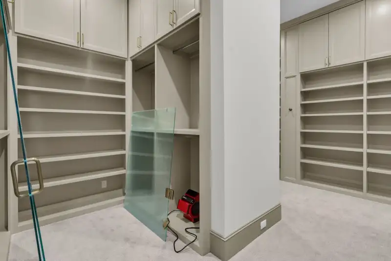 Closet with open shelving, a hanging rod, and a glass panel leaning against the wall.