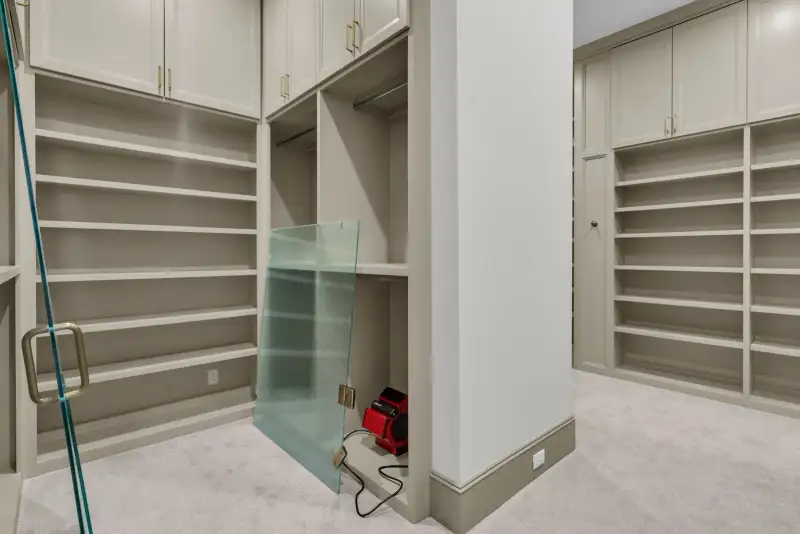 Closet with open shelving, a hanging rod, and a glass panel leaning against the wall.