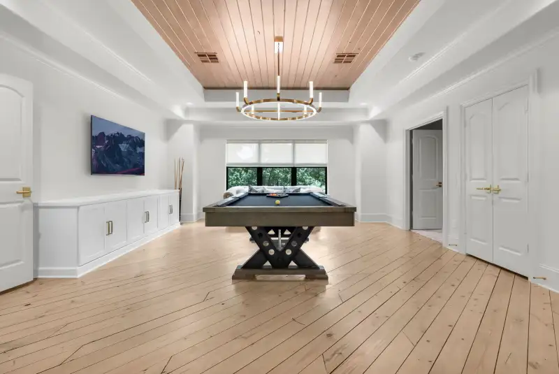 Game room with a wood plank tray ceiling, a pool table, a built-in cabinet, and a wall-mounted television.