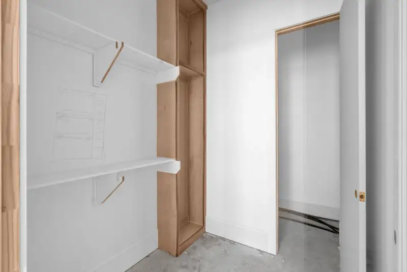 Closet with a white wall shelf, a wood storage tower, and an open door.