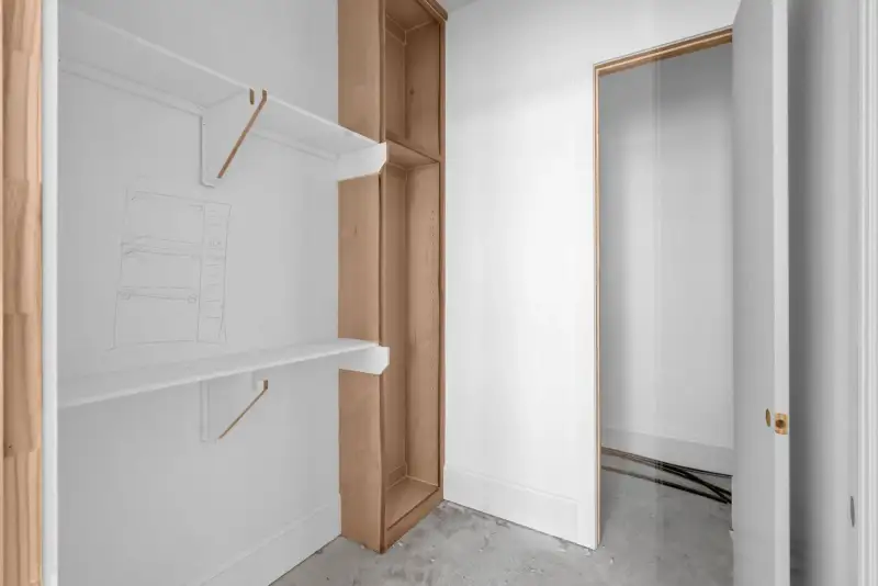 Closet with a white wall shelf, a wood storage tower, and an open door.