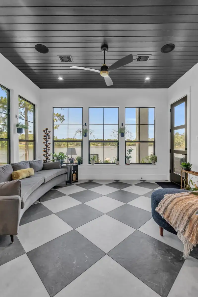 Sunroom with a checkered tile floor, black-framed windows, a dark plank ceiling, and a ceiling fan.