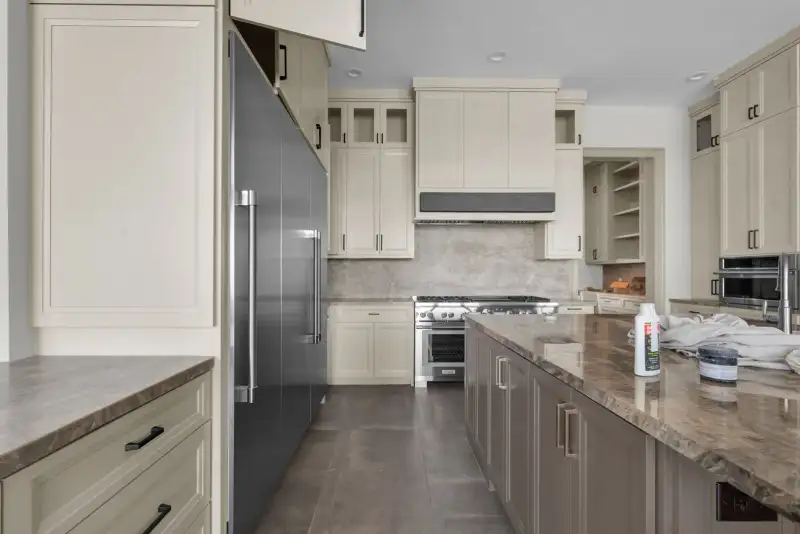 Kitchen with light cabinets, a stainless range, and a stone backsplash.