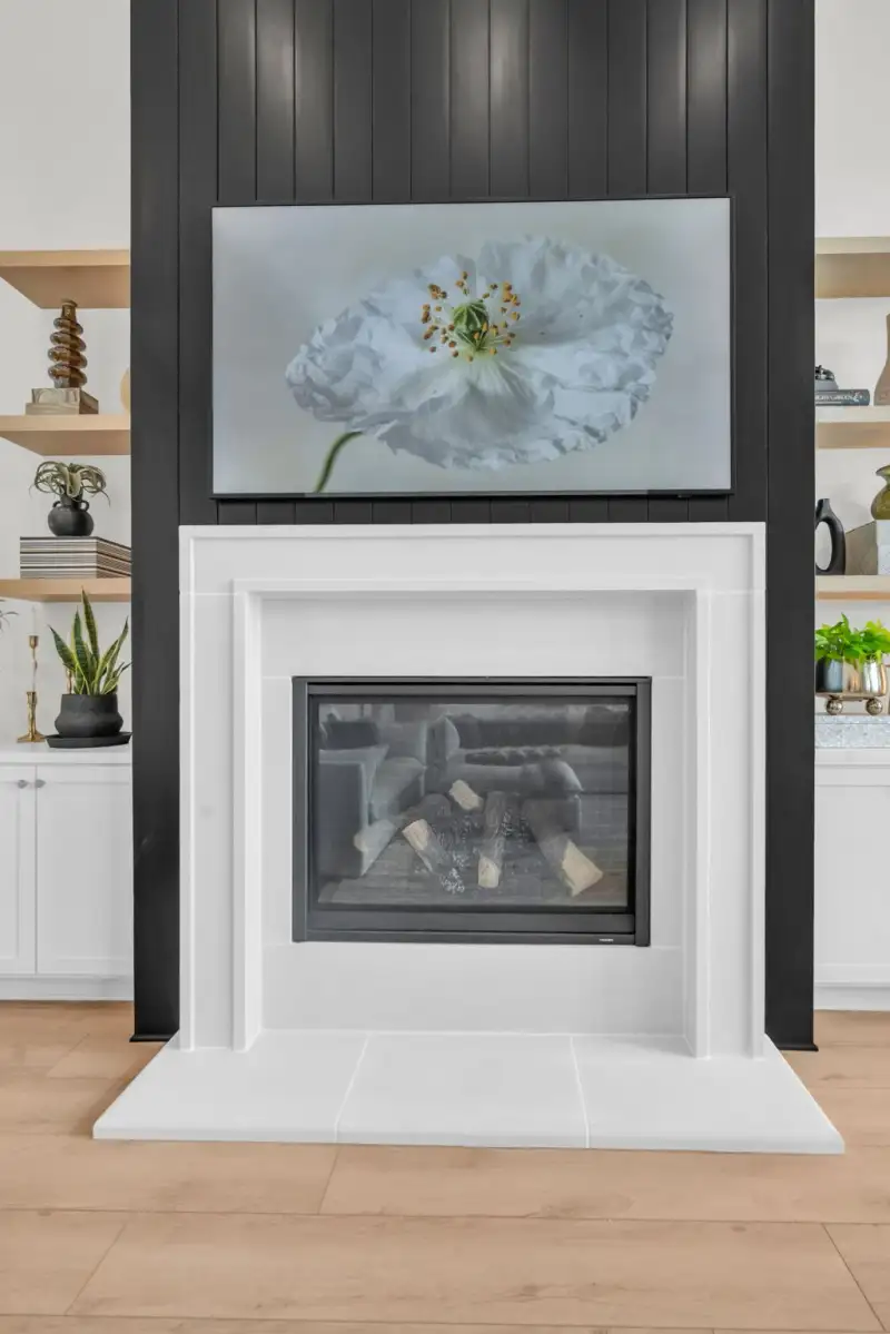 Fireplace with a white surround under a black shiplap wall, with a television above showing a flower image.