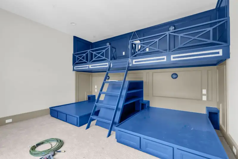 Bedroom with built-in blue bunk beds, a ladder, and an upper loft.