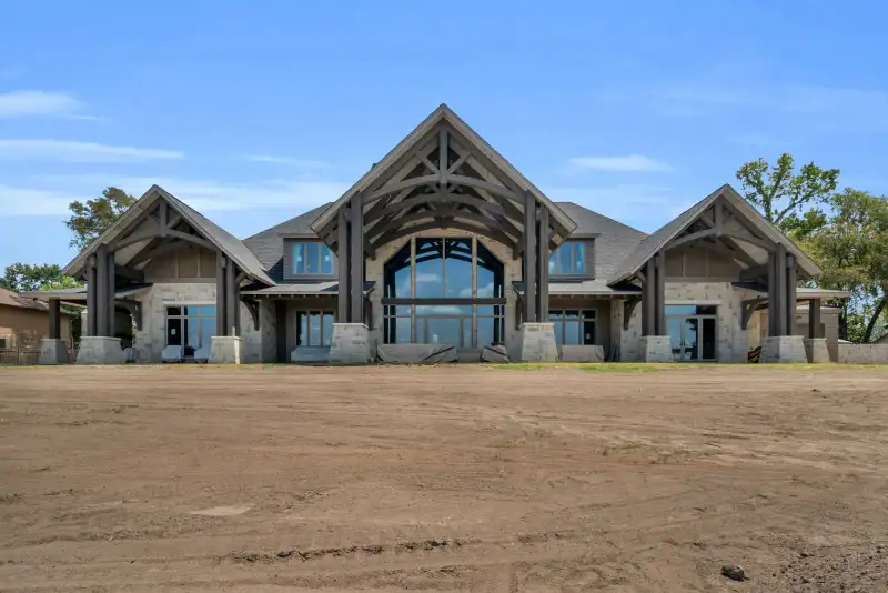 Exterior elevation of the home with timber gables, stone columns, and a tall arched window.