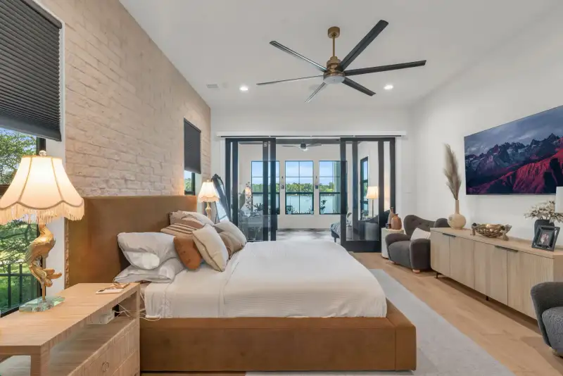 Bedroom with a brown upholstered bed, glass sliding doors to an outdoor area, and a large mountain photograph.