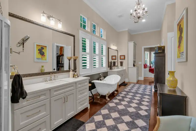 Primary bath with a double vanity, a framed mirror, a clawfoot tub, and a crystal chandelier.
