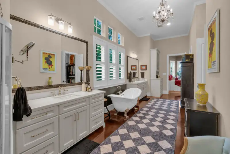 Primary bath with a double vanity, a framed mirror, a clawfoot tub, and a crystal chandelier.