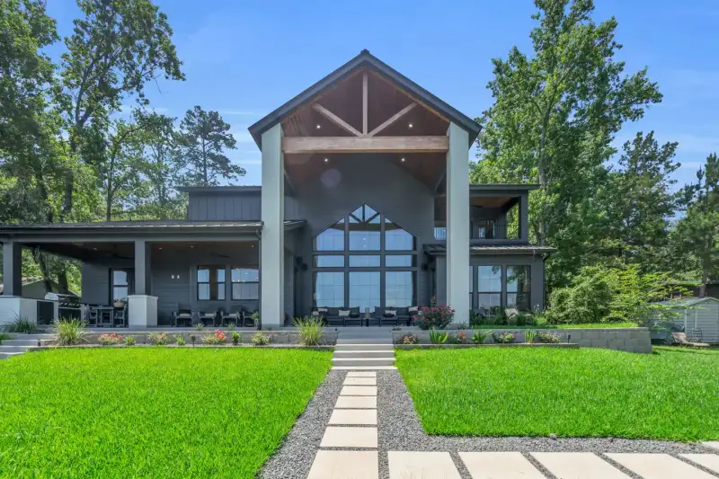 Rear facade with a gabled roof, tall arched windows, and a stone walkway across a lawn.