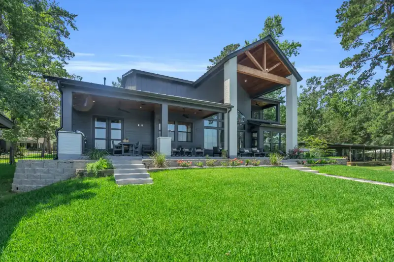 Rear view of the home across a lawn, with a covered patio and gray siding.