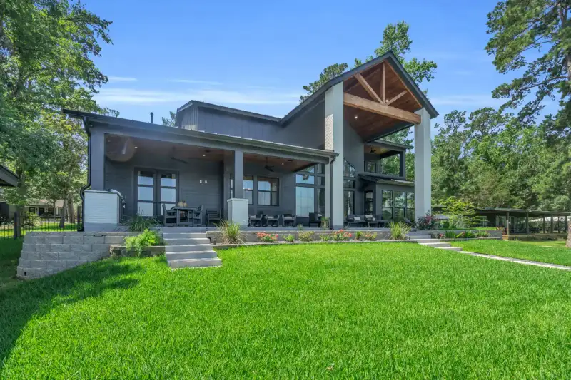 Rear view of the home across a lawn, with a covered patio and gray siding.