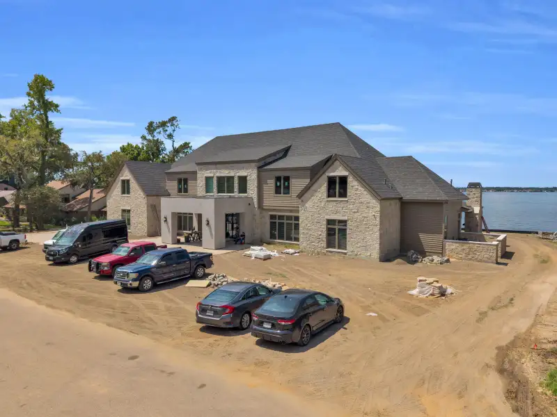 Aerial view of the Escondido home's driveway and lakefront, with parked vehicles and open water beyond.