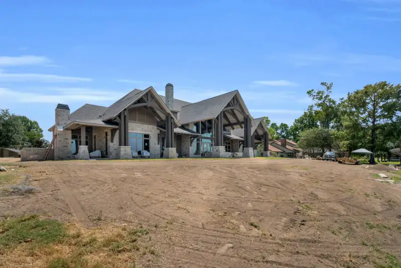 Exterior of the home with a gabled roof, stone columns, and a covered patio along the side.