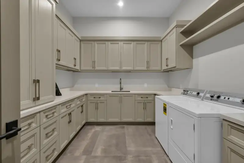 Laundry room with light cabinets, a sink, and a washer and dryer along the wall.