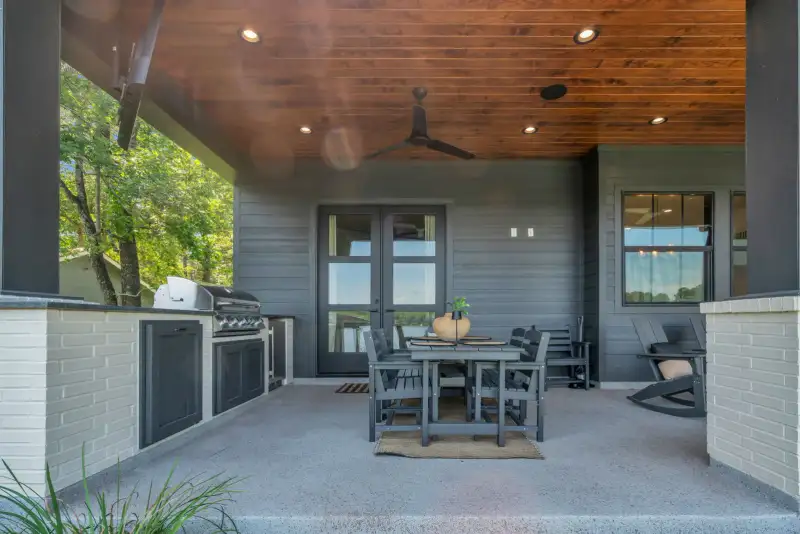 Covered patio with a wood ceiling, a built-in grill, a dining table, and French doors.