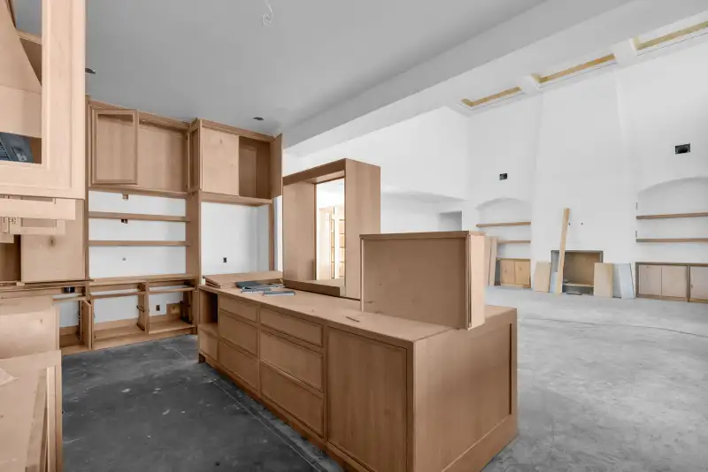 Kitchen with a wood island and cabinets, and a room with a coffered ceiling beyond.