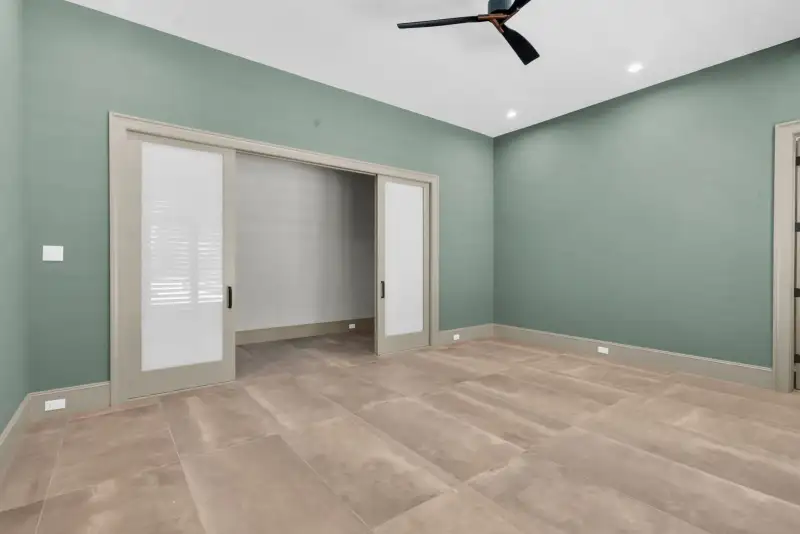 Room with green walls, frosted pocket doors, and a ceiling fan.