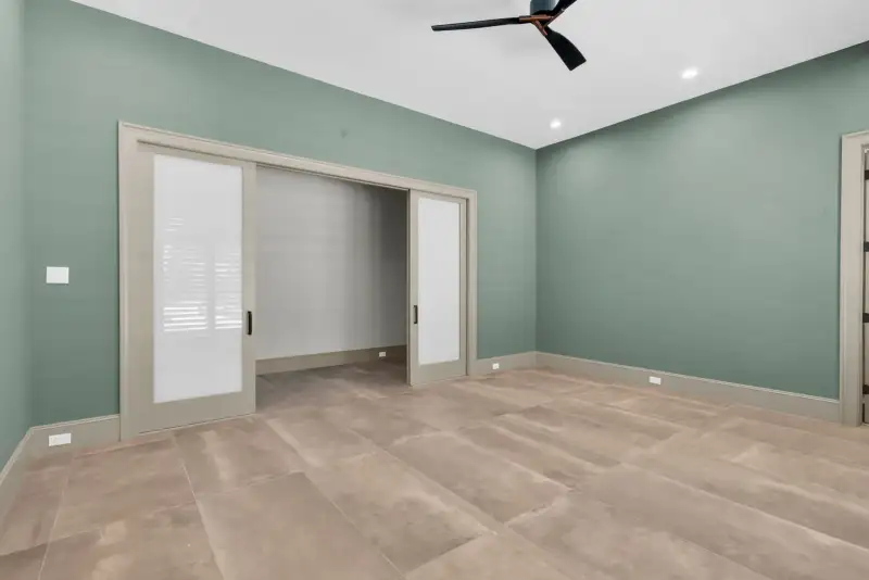Room with green walls, frosted pocket doors, and a ceiling fan.