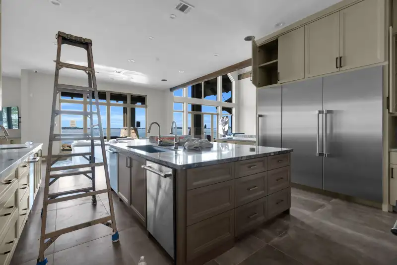 Kitchen island with a sink, a stainless dishwasher, and a stainless refrigerator beside it.