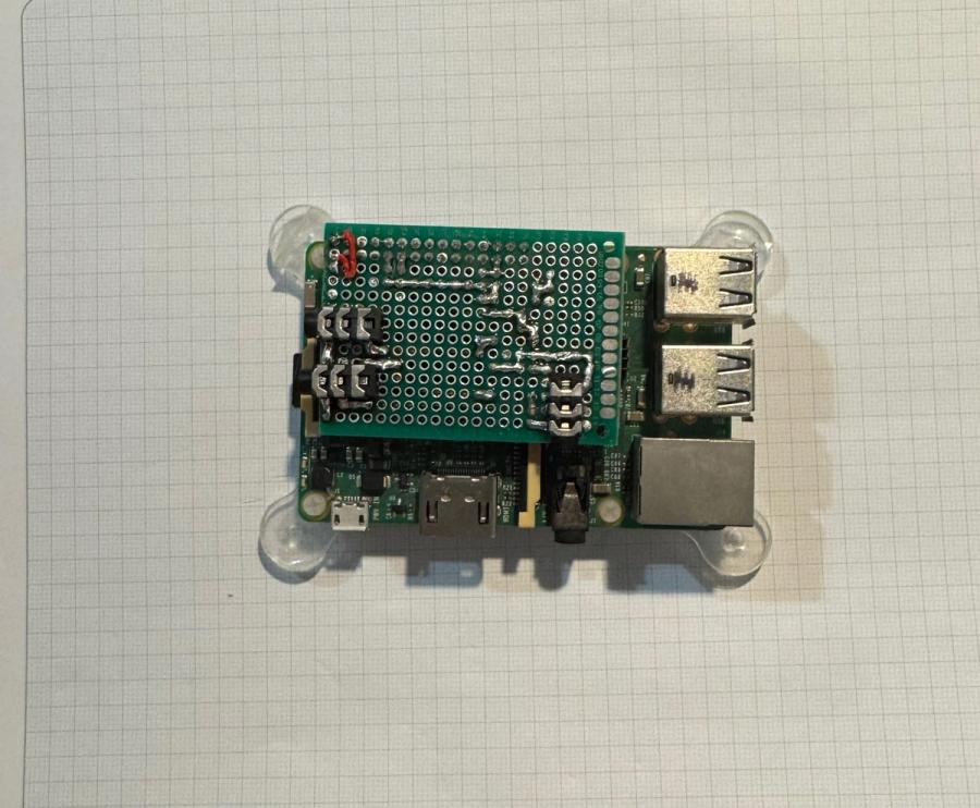 Completed audio switcher HAT mounted on a Raspberry Pi 3B, showing the perfboard assembly, relay, audio connectors and GPIO connection.