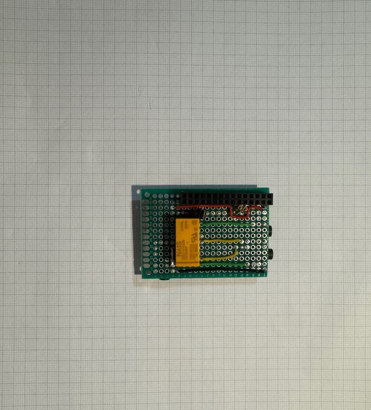 Component side of the completed audio switcher HAT showing a yellow relay, GPIO header, connecting wires and three audio sockets.