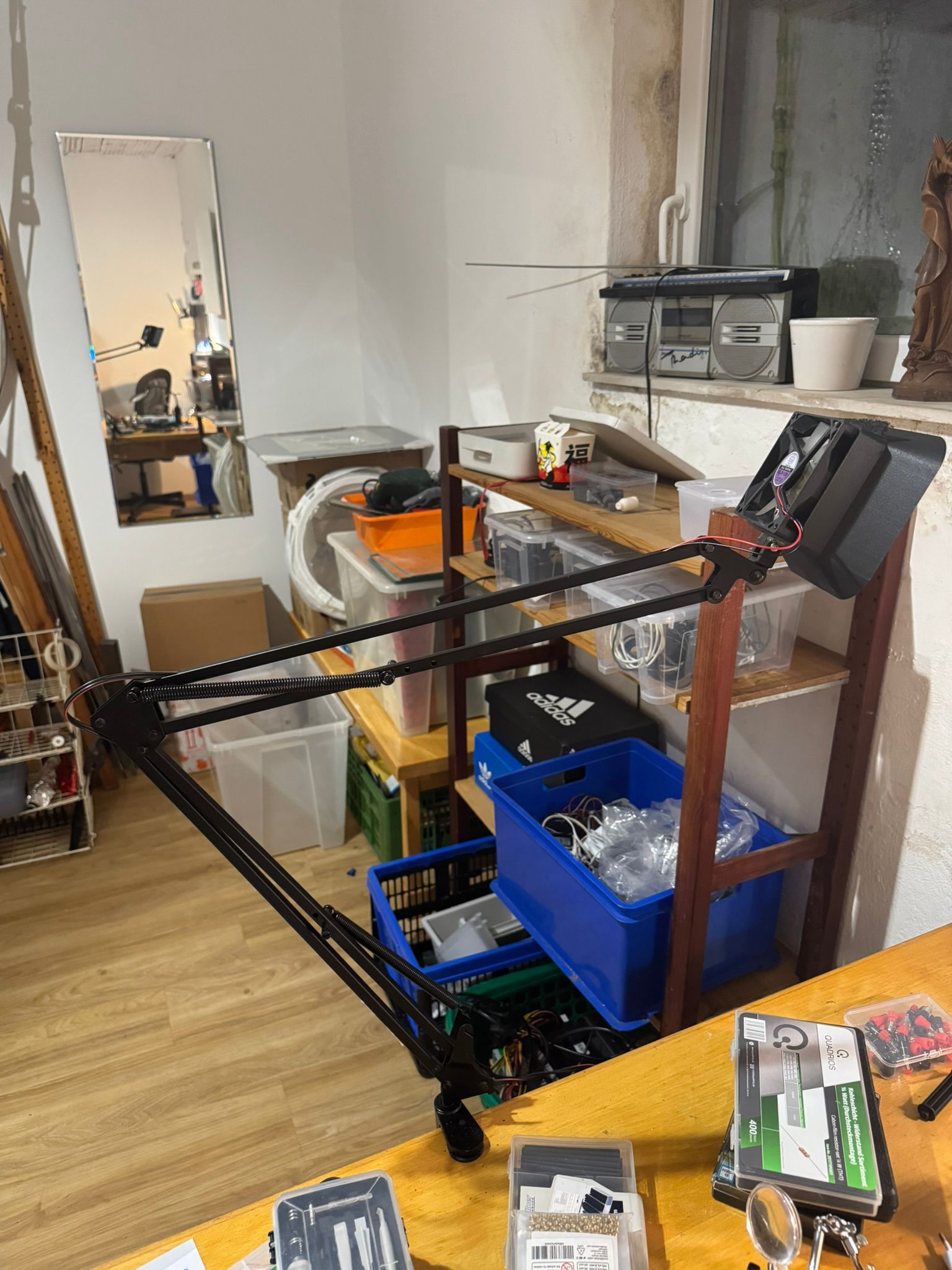 Overview of the 3D printed fume extractor mounted on a black articulated microphone arm attached to a wooden shelf