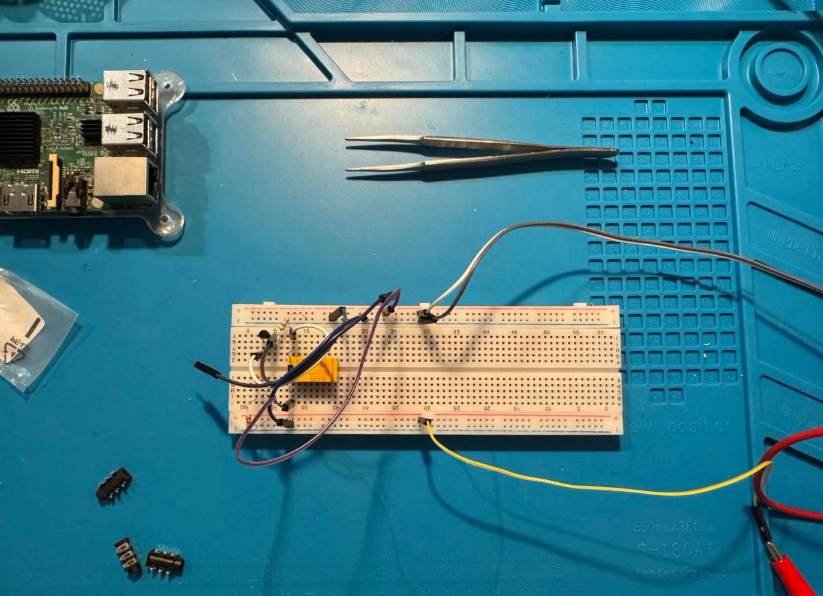 Breadboard prototype of the audio switcher containing a relay, transistor, resistors and jumper wires, with a Raspberry Pi positioned nearby.