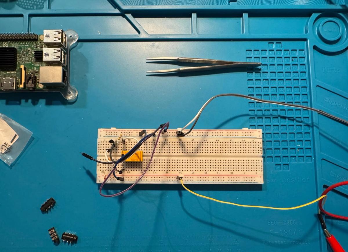 Breadboard prototype of the audio switcher containing a relay, transistor, resistors and jumper wires, with a Raspberry Pi positioned nearby.