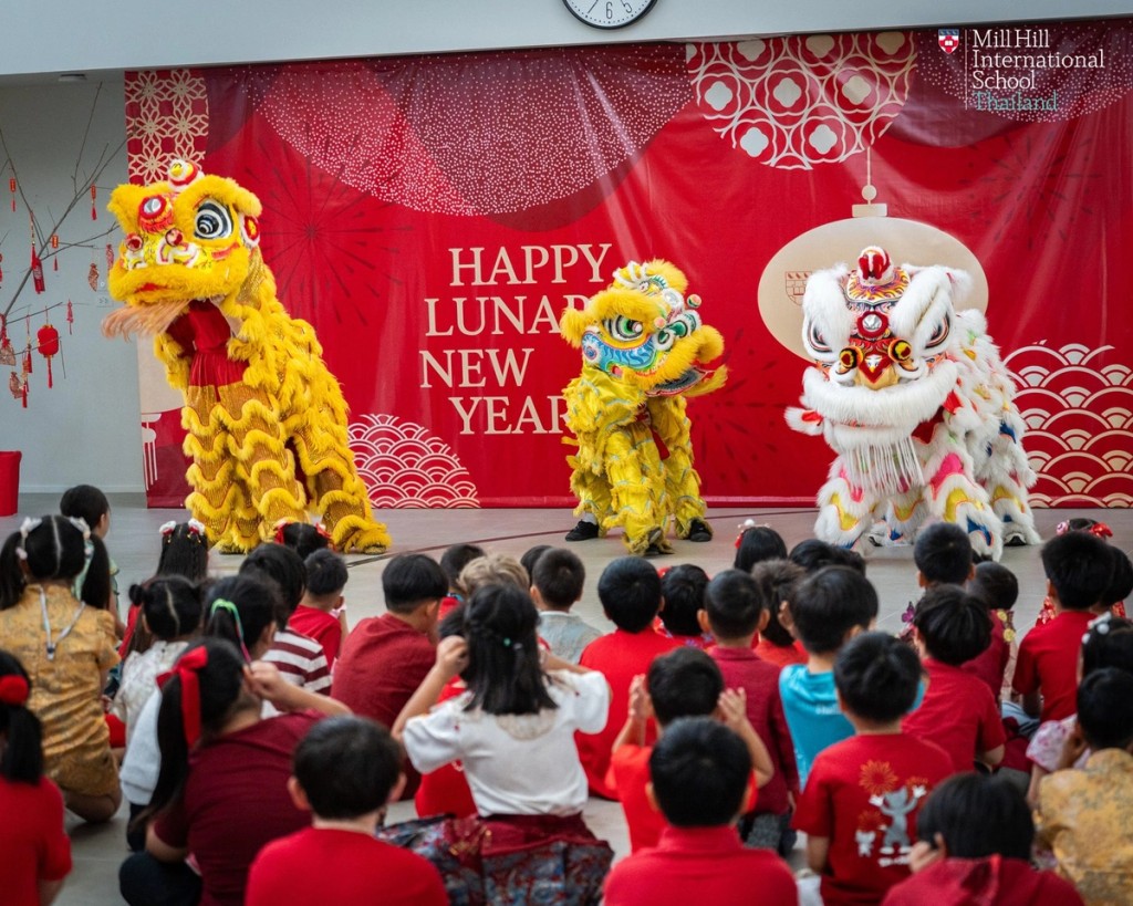 Lion dancers performing in front of a Happy Lunar New Year banner at Mill Hill International School Thailand